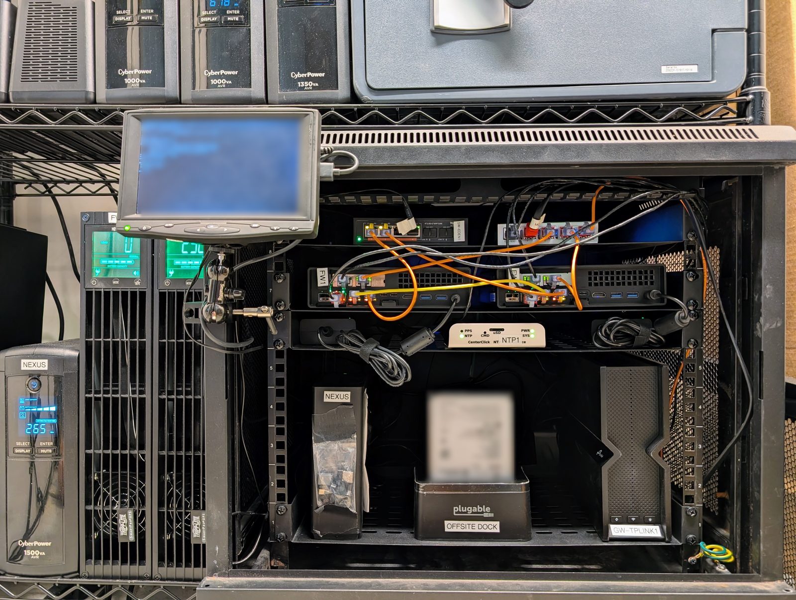 A small enclosed rack holding two compact firewalls, a time server, a backup dock and a consumer gateway