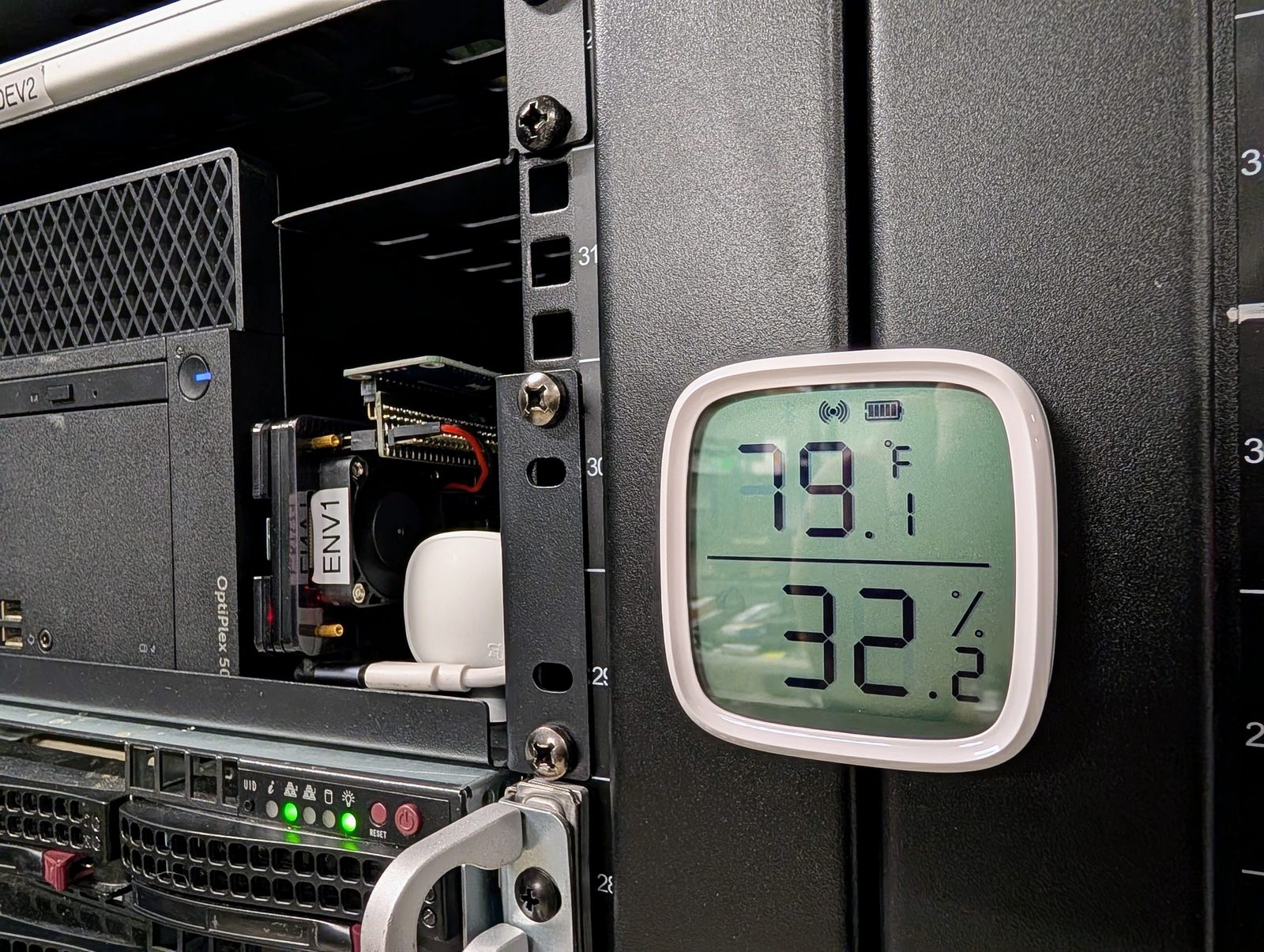 A small temperature and humidity display clipped to a rack post