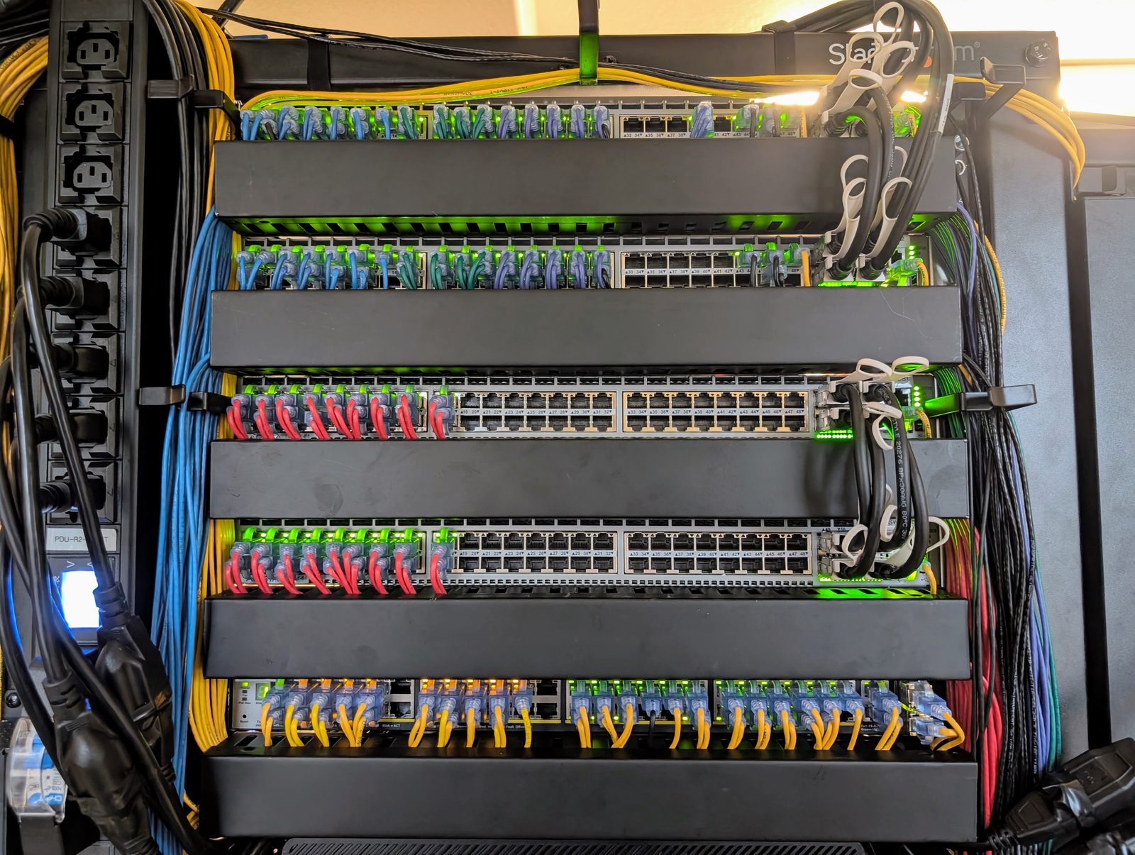Five rows of switches seen from the front, patch cables running out of them in the colours of the cabling standard