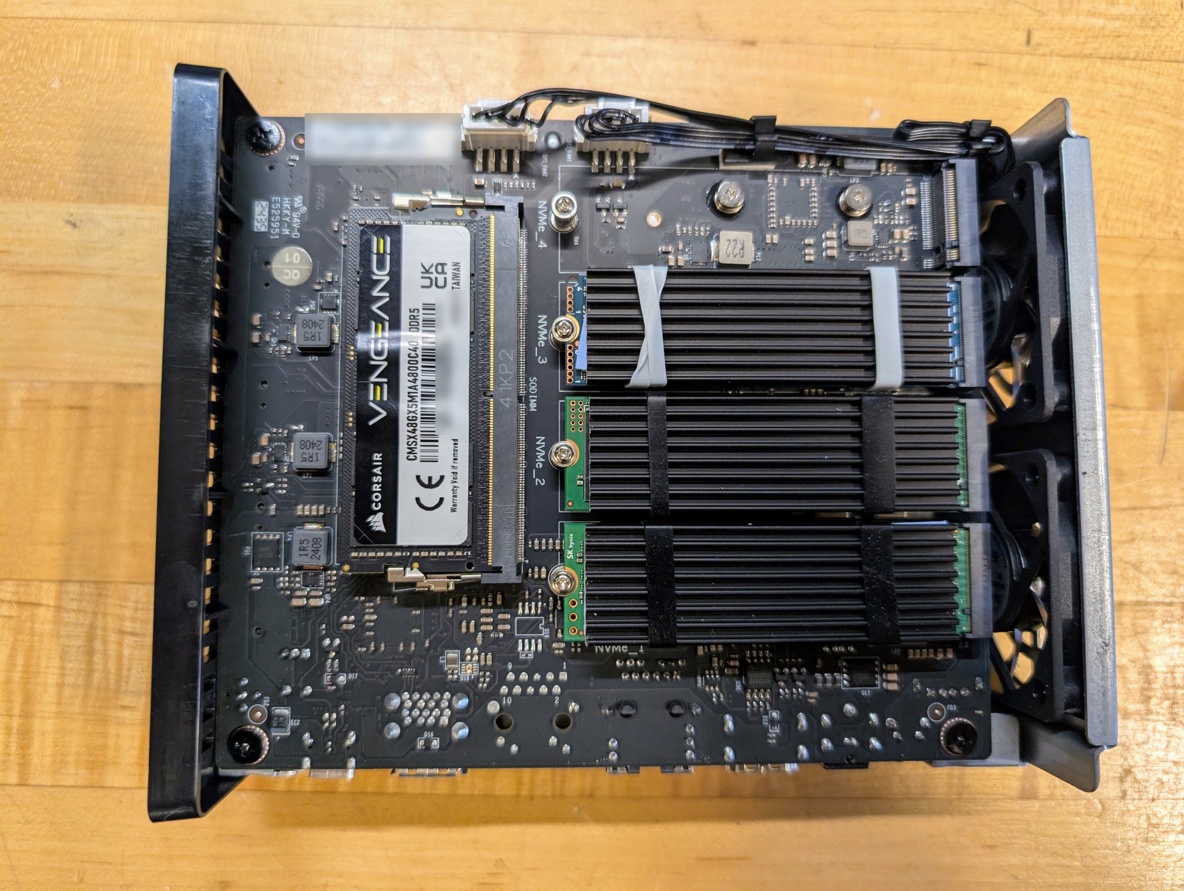 The circuit board of the NAS from above: one laptop-size memory module on the left, three drives under black finned heatsinks on the right, and an empty slot above them.