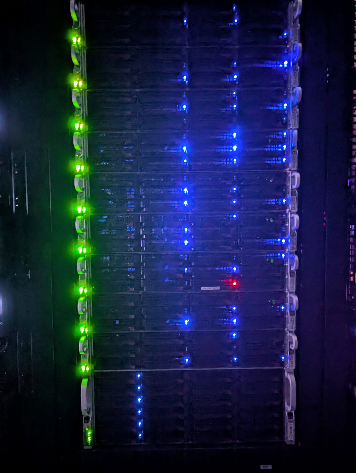 A rack of storage servers in a darkened room, drive activity showing as blue points down the full height of the rack